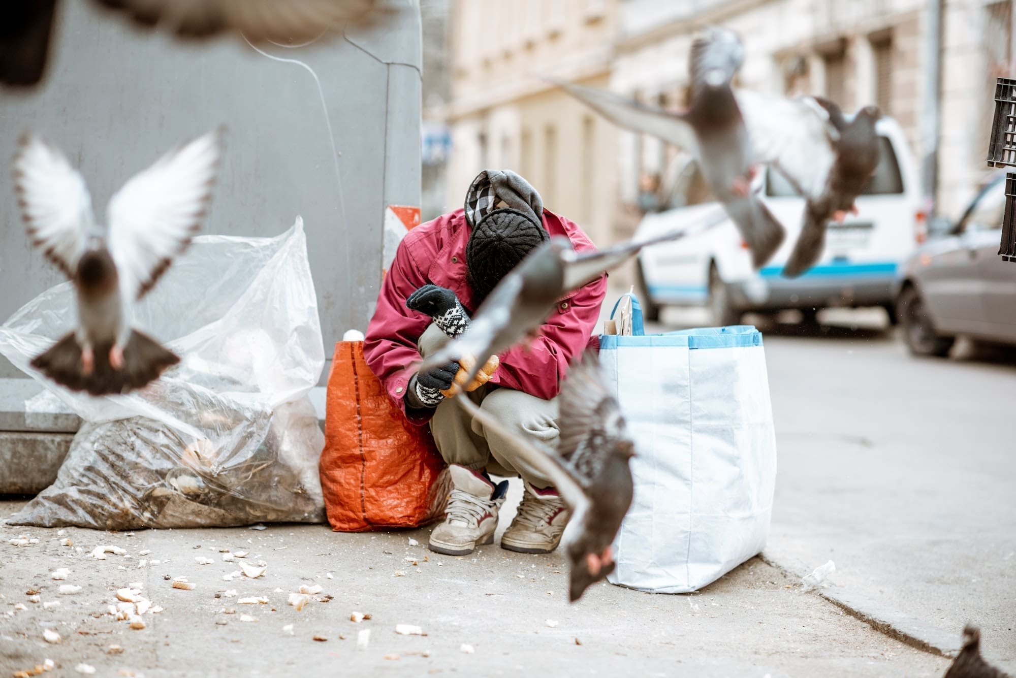 Homeless beggar near the trash in the city