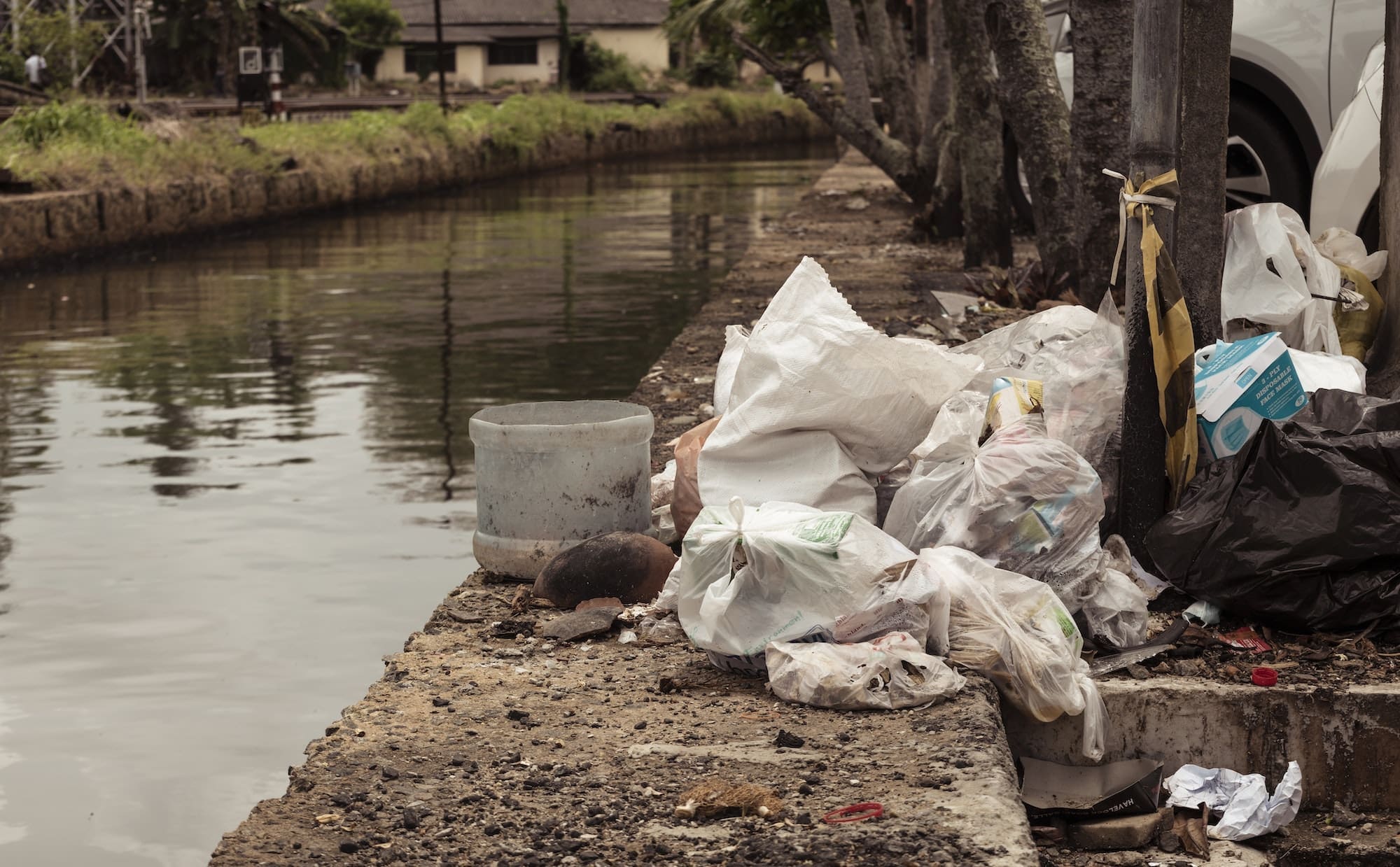 Pile of polythene bags and trash in the streets near a lake.